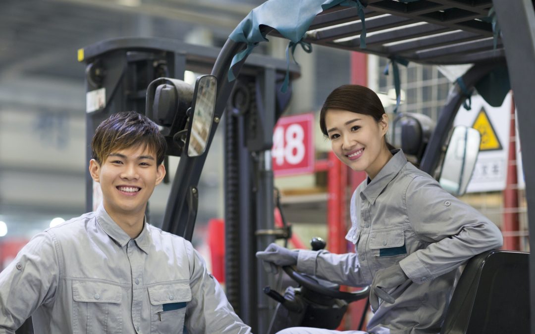 Confident workers driving forklift in the factory