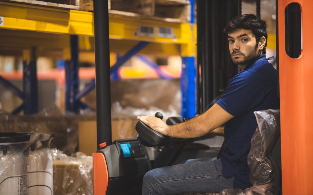 Young forklift driver sitting in vehicle in warehouse