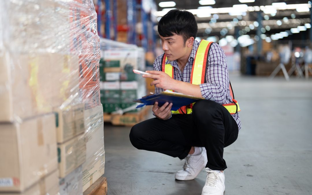 Worker working in large warehouse holding paper chart