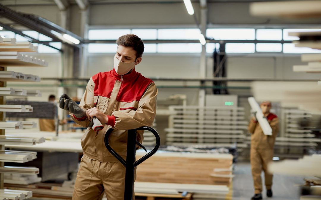 Manual worker using protective gloves while working at carpentry warehouse.