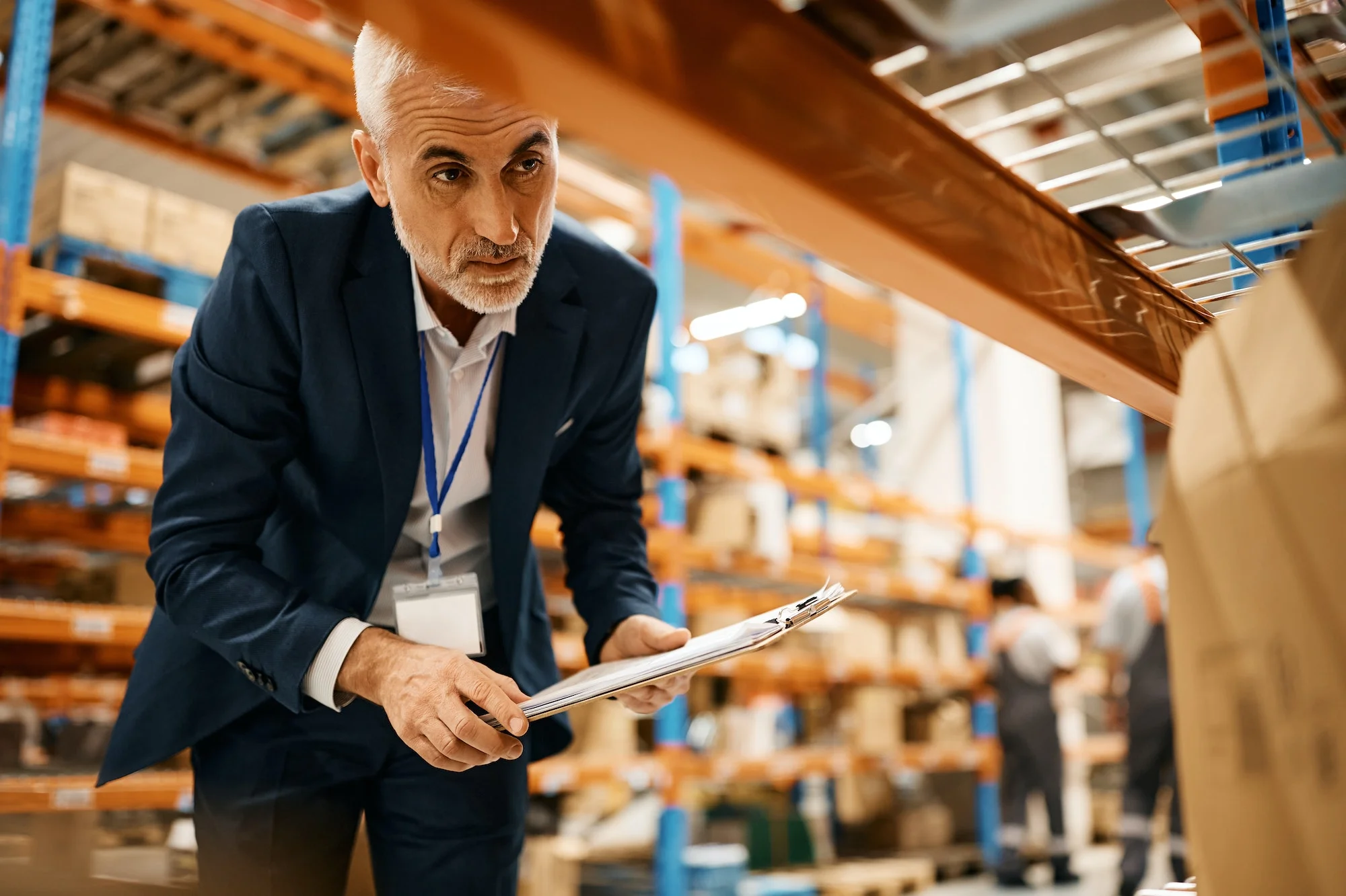 Mature warehouse manager checking stock of packages at storage compartment. Material Flow Analysis: A Step-by-Step Guide to Evaluating and Optimizing Your Warehouse