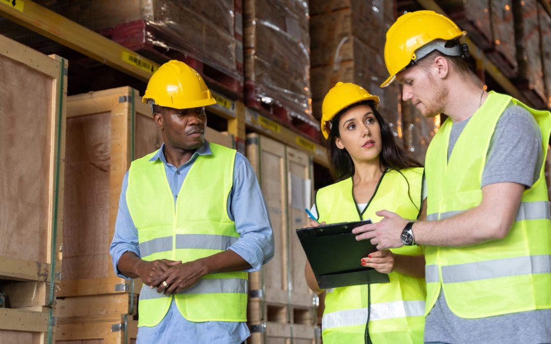 Three male and female warehouse workers are working in a warehouse