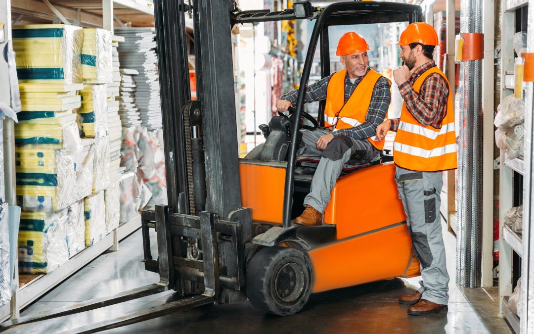 two male workers using forklift machine in storehouse