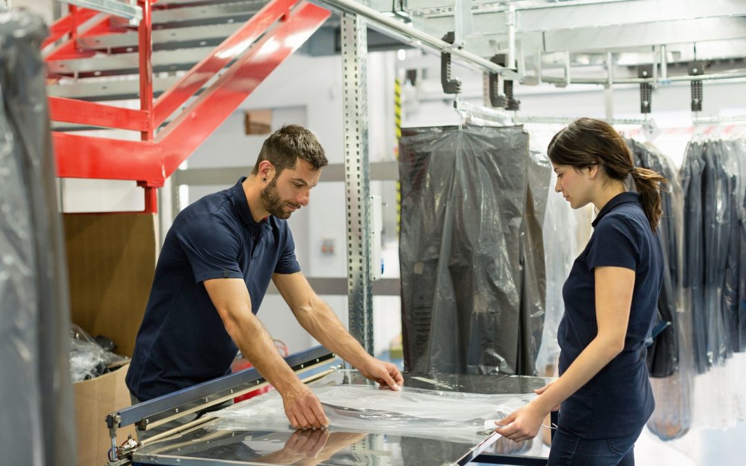 Warehouse workers wrapping garment stock in plastic in distribution warehouse